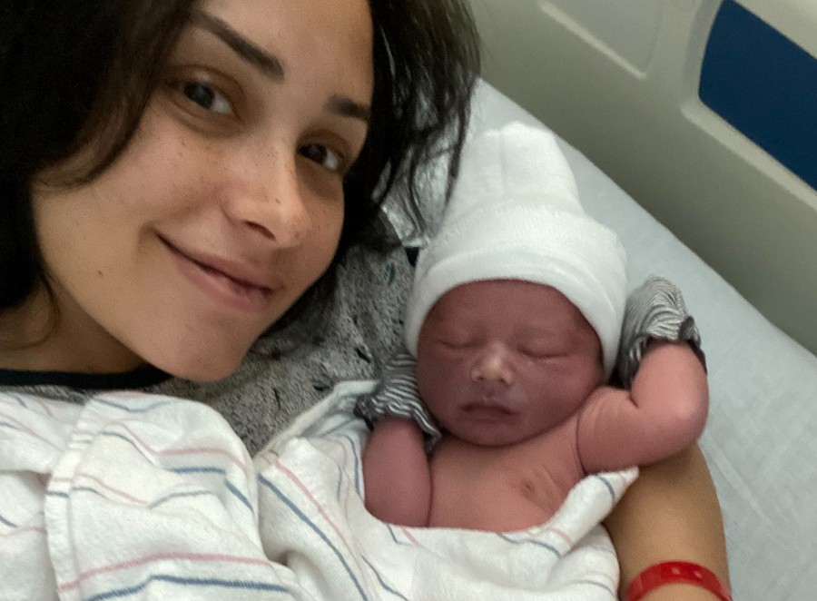 A smiling woman cradles her newborn infant in her hospital bed.