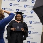 A photographer takes a professional portrait of Nicole Waweru, a graduate of the Master of Public Health Program at Penn State College of Medicine, during the 51st commencement.