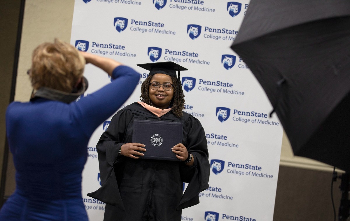 A photographer takes a professional portrait of Nicole Waweru, a graduate of the Master of Public Health Program at Penn State College of Medicine, during the 51st commencement.
