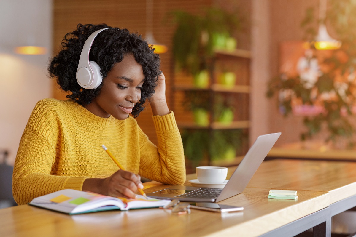 A woman sits in front of a computer with headphones on.