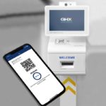 A smartphone with a QR code on it is shown in front of a kiosk that has the GHX Vendormate logo on it. The bottom of the kiosk says “welcome.”