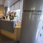 The lobby of the Cancer Assistance and Resource Education Center in Penn State Cancer Institute shows a reception desk with a bowl of flowers on it, a column on the right with the words “CARE Center Lobby” on it and a wall with slats on the left.