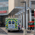 An ambulance sits outside the front entrance of an emergency department