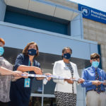 A group of officials cut a ribbon outside of a new medical practice