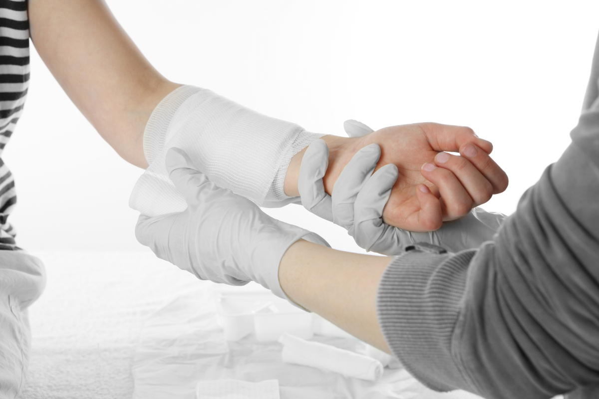 A close up of a provider dressing a wound on a patient's arm