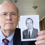 Cheston Berlin, MD, holds up a photograph of himself from 50 years earlier.