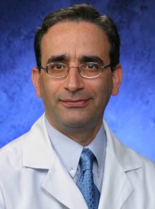 Dr. Nasr Ghahramani, wearing a white coat, poses for a professional headshot. 