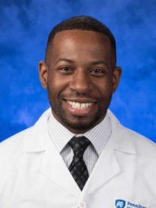 Dr. Ify Ndukwu, wearing a white coat, poses for a professional headshot.