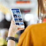 A woman holds up a cell phone.