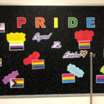 A bulletin board titled PRIDE Beyond the Rainbow includes images of differently colored LGBTQ+ Pride flags with small bubbles describing them.