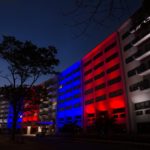 Exterior photo of the front of Milton S. Hershey Medical Center curved crescent lit in red, white and blue.