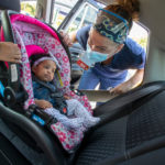 A woman checks a baby's car seat