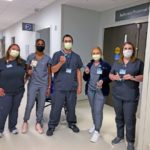 Four women and one man who are members of the Hampden Medical Center respiratory team stand in a hallway. Four of them hold flowmeter devices. They are wearing scrubs, masks and nametags.