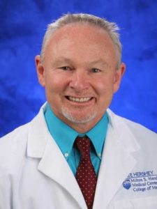 Dr. Timothy Craig poses for a professional headshot wearing a white coat against a studio background