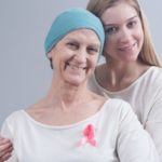 A woman with breast cancer poses with her daughter. Both are smiling.