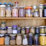 A cupboard contains jars of dry goods.