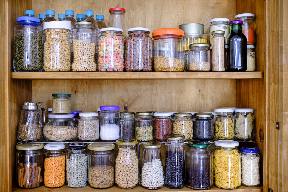 A cupboard contains jars of dry goods.