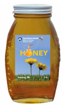 A glass jar of honey bears a label that reads Penn State Health Honey and has pictures of flowers and bees.