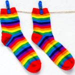 Close-up of pair of rainbow-colored socks hanging from clothesline.