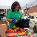 Christina Houston, miembro del personal de Blue Mountain Academy, organiza frutas y verduras para venta en el puesto de agricultura del campus del centro de Penn State Health St. Joseph.