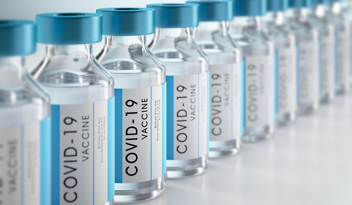 A row of vaccine vials displays labels indicating they are for COVID-19.