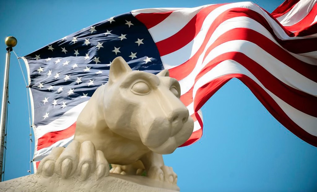A Nittany Lion statue in the foreground, with an American flag in the background.