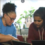 A mother and her daughter look at photographs in their home.