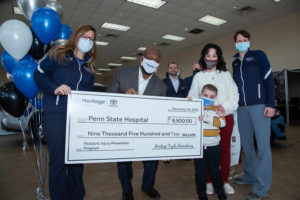 Four adults and a child pose with an oversized check in the amount of $9,500 made payable to Penn State Health Children’s Hospital’s Pediatric Injury Prevention Program.