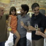 A family raises champagne flutes for a holiday. There are four adults and a child. The child holds a glass of juice.