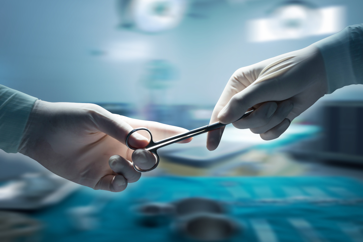 Close-up of two gloved hands handing off a piece of equipment in an operating room.