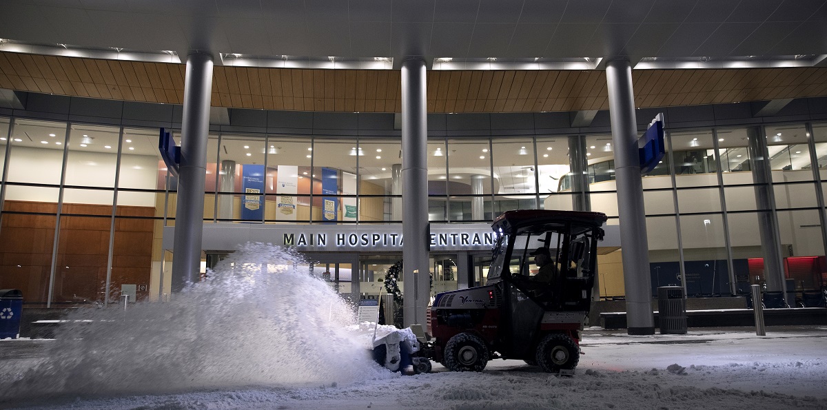 A plow pushes a pile of snow in front of the entrance to Hershey Medical Center.