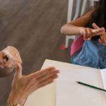Caucasian female teacher wearing face mask at school, teaching children at school classroom. Education back to school health safety during Covid19 Coronavirus pandemic.