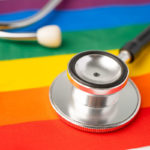 Black stethoscope on rainbow flag background, symbol of LGBT pride month celebrate annual in June social, symbol of gay, lesbian, bisexual, transgender, human rights and peace.