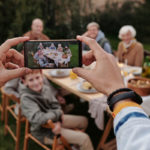 Unrecognizable person taking photo of family dinner on smartphone