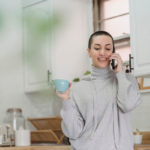 Cheerful woman talking on smartphone in kitchen
