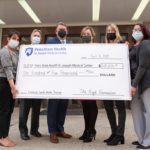 Six people pose with an oversized check in front of a building. The check, in the amount of $105,000, is from the High Foundation and made payable to Penn State Health St. Joseph Medical Center.
