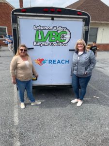 Madeline Bermudez, left, community health worker, and Andrea Murray, REACH director, stand outside in front of a trailer during the Lebanon Bicycle Recycle open house in Lebanon on March 19, 2022. Penn State REACH is a partner on the LBR initiative. 