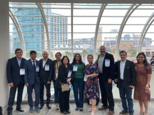 A group of 10 researchers, including Penn State College of Medicine faculty members and researchers Dr. Prashant Nighot and Dr. Meghali Nighot, pose for a group photo against a large glass window during the Digestive Disease Week conference. 