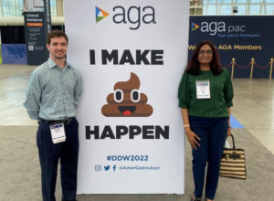 Nathan Morris and Dr. Meghali Nighot stand on either side of a large sign proclaiming Digestive Disease Week, a scientific conference for gastroenterology and digestive disorders.