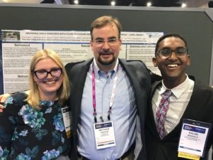 Izabela Zubrzycka, left, Dr. Matthew Coates and Kaleb Bogale stand in front of a poster board at Digestive Disease Week.