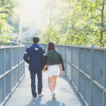 Man and Woman Holdings Hands While Walking on Bridge