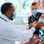Doctor cares for pediatric patient while mother looks on.