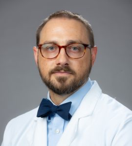 Dr. Jason Webb, wearing glasses and a white coat, poses for a professional headshot.