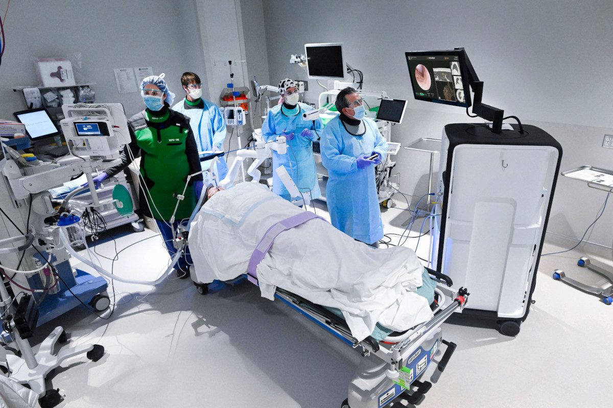 A physician looks at a screen while performing a bronchoscopy as staff members look on.