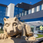 A photo of the Nittany Lion statue in front of a hospital