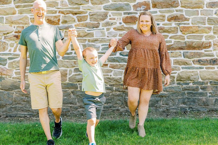 Two young parents and their young child outside smiling