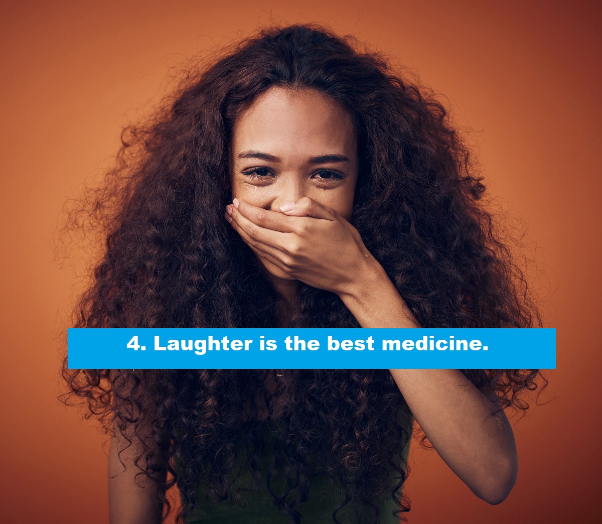 Shot of a woman with curly hair covering her mouth while laughing.