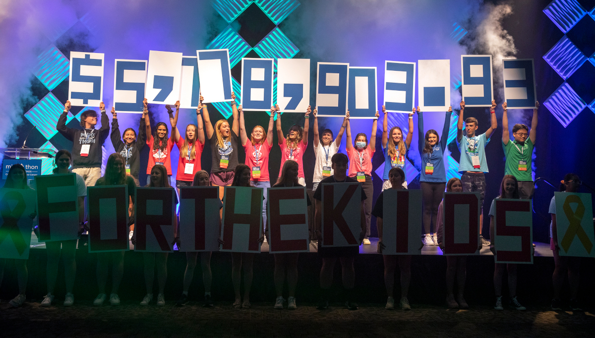 Students hold up signs with numbers on them to reveal a fundraising total of more than $5.7 million