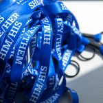 Pile of blue lanyards, each with the words “she/her,” “him/his” or “they/them”