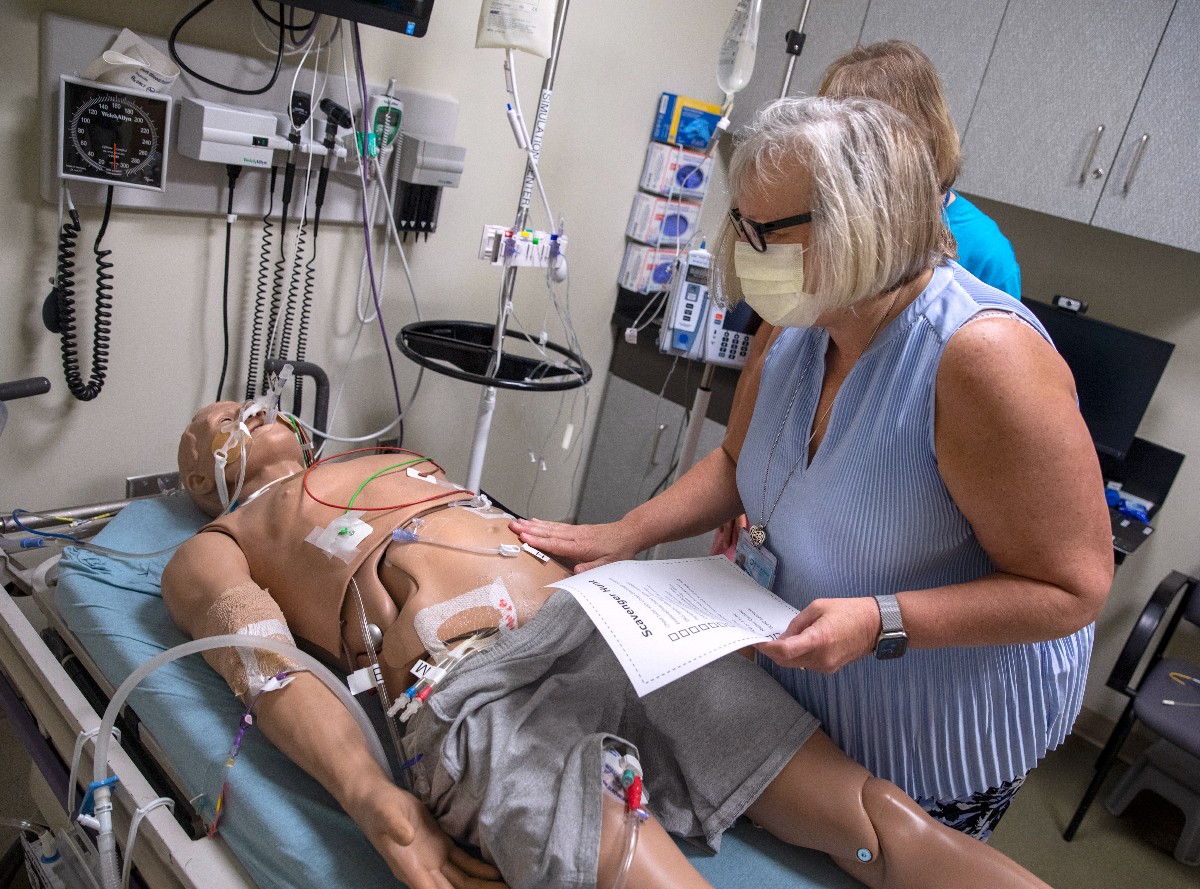 Dr. Susan Promes searches for various pieces of medical equipment on a mannikin in the Simulation Center.